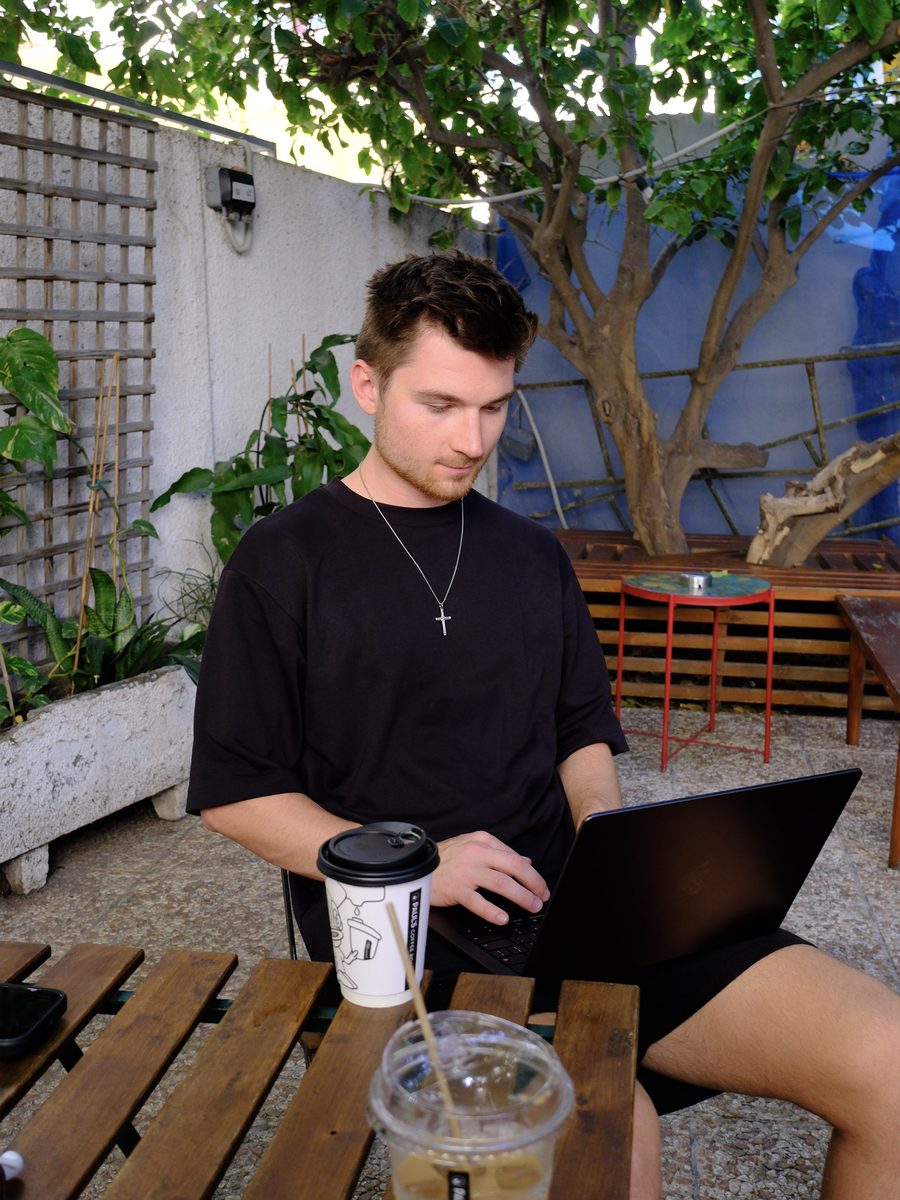 Alex working on a laptop with coffee in the courtyard at Paul's Coffee Roasters in Larnaca
