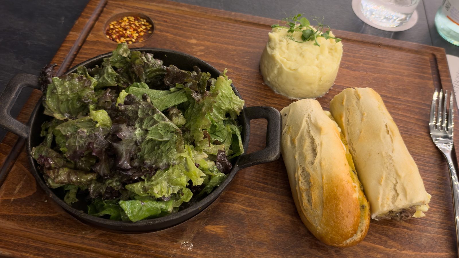 Beef-filled baguette with mashed potatoes and a salad on a wooden board at Rise Urban Art Hotel in Larnaca