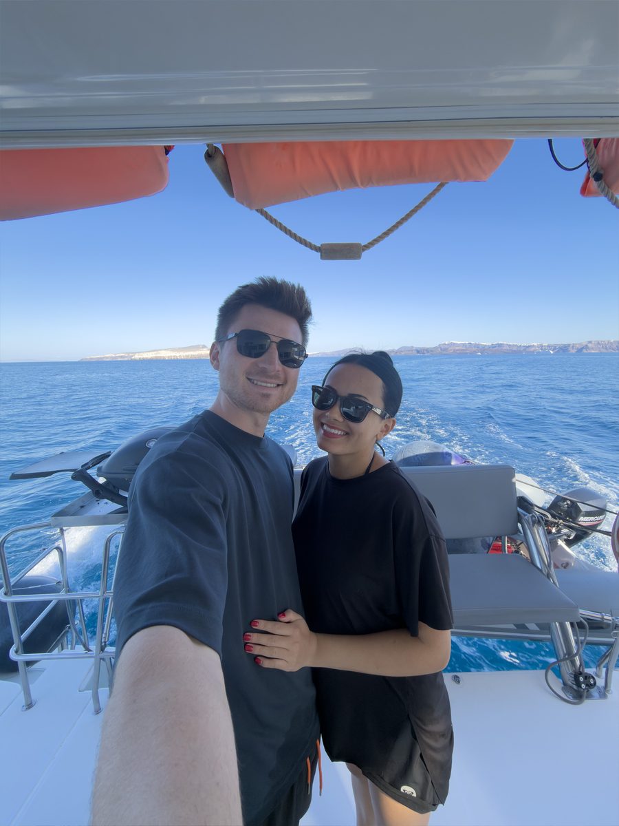 Alex and Megan Colhoun on the back deck of a catamaran cruise sailing the Santorini caldera