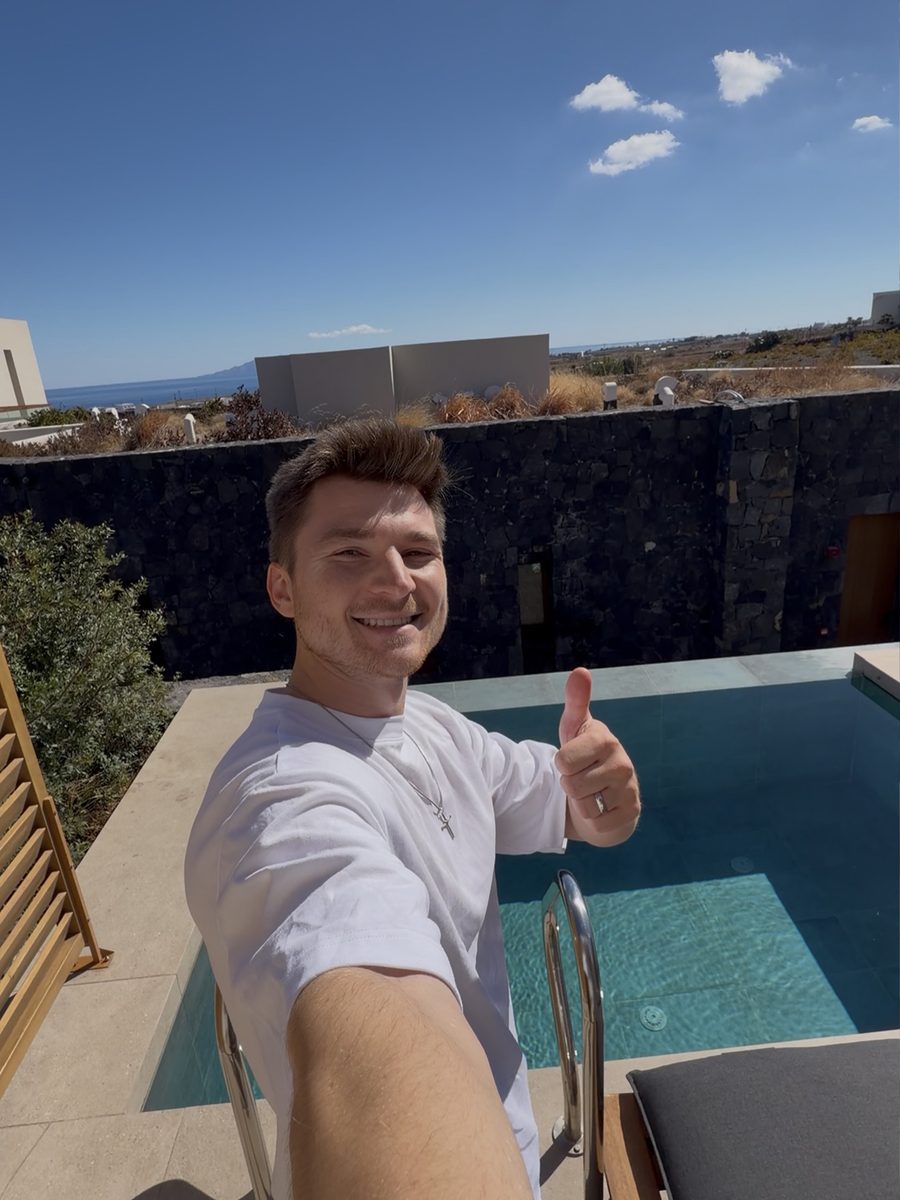 Alex giving a thumbs up by the private hot tub on the terrace of our upgraded room at Magma Resort Santorini