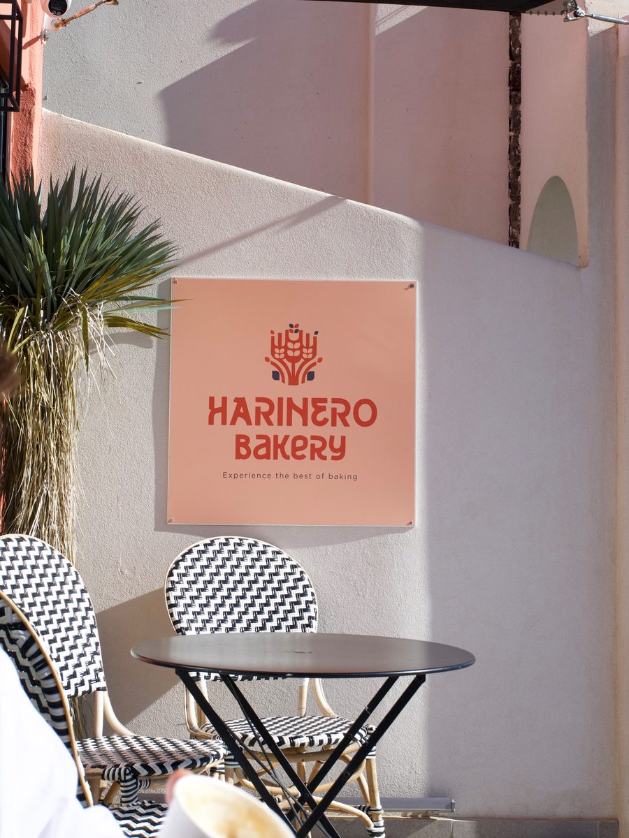 Harinero Bakery sign above a cafe table and wicker chairs in Kamari, Santorini