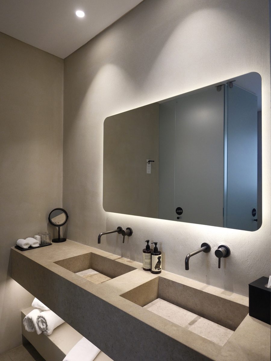 Stone double vanity with a backlit mirror in the bathroom of our room at Magma Resort Santorini