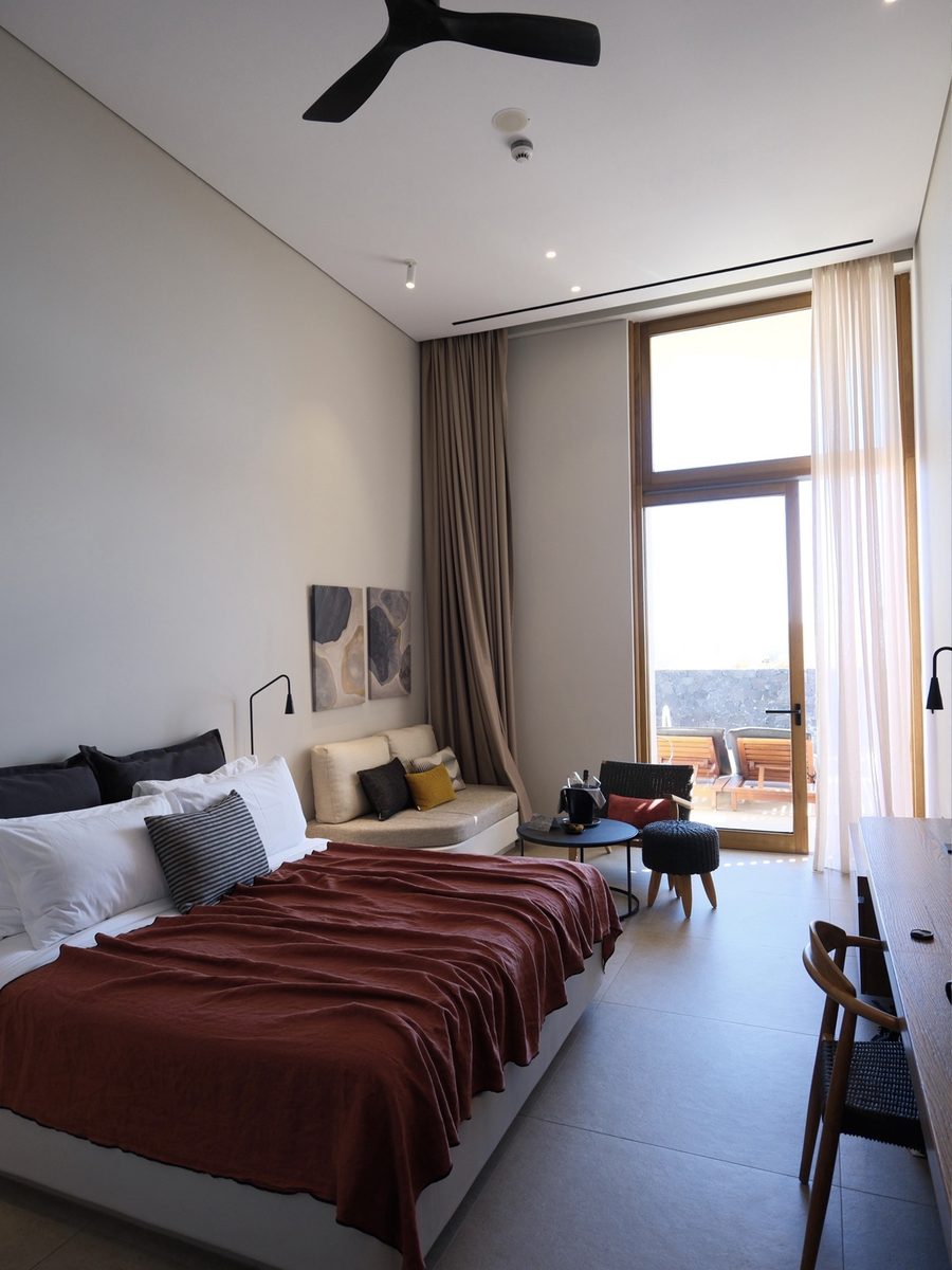 Upgraded room at Magma Resort Santorini with a king bed, sofa, high ceilings and doors to a private terrace