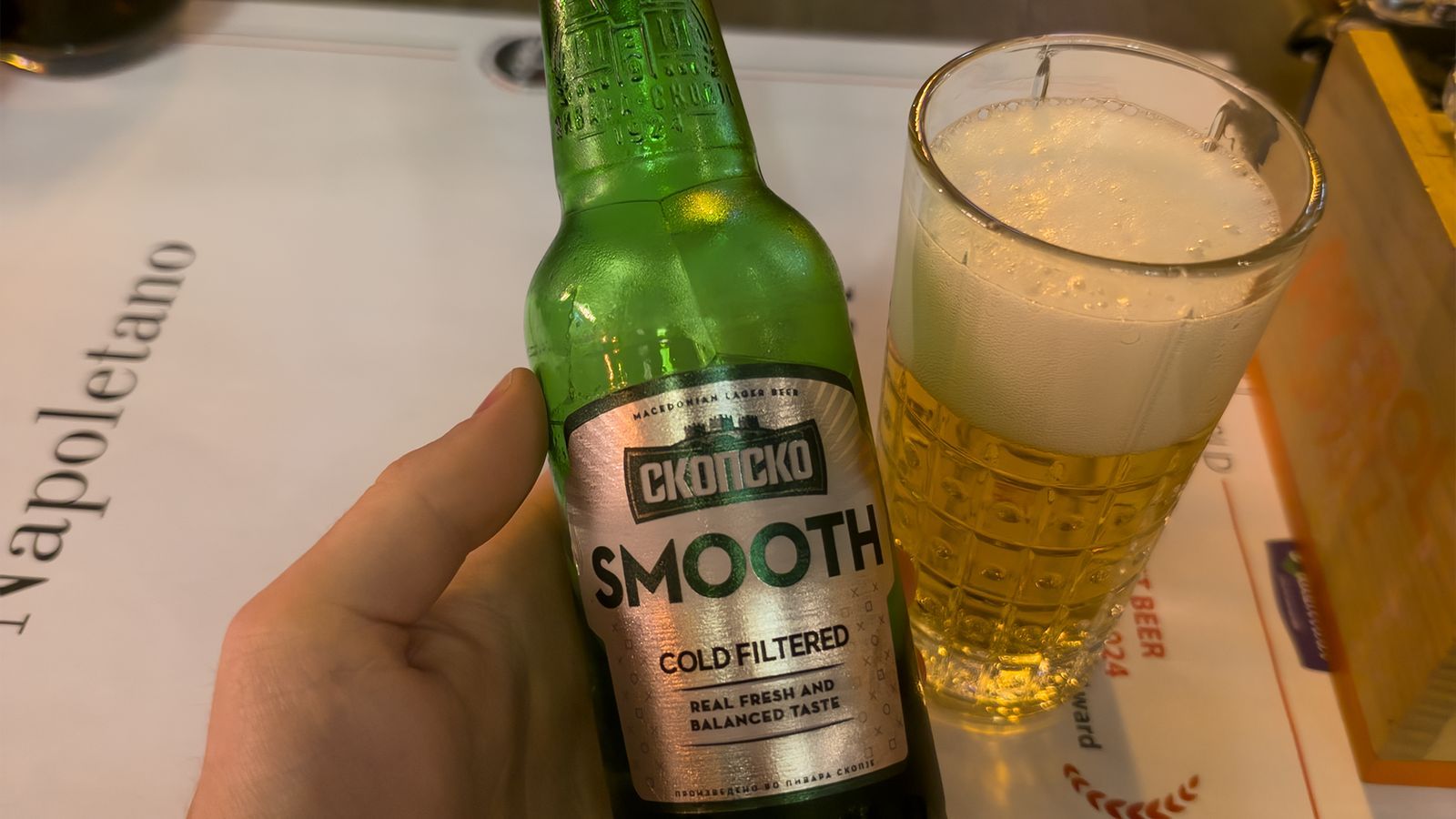 A bottle of Skopsko Smooth Macedonian lager next to a full glass of beer at Matto Napoletano
